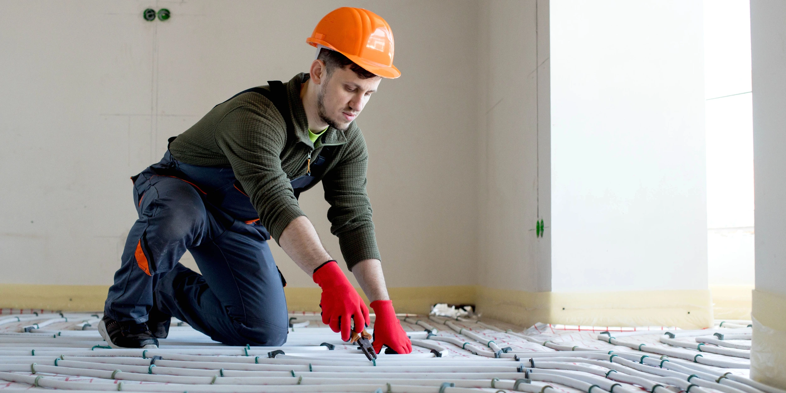 Un jeune homme posant le système d'un plancher chauffant - photo de couverture de l'article Plancher chauffant glycol ou eau Guide pour maisons de la Rive-Sud